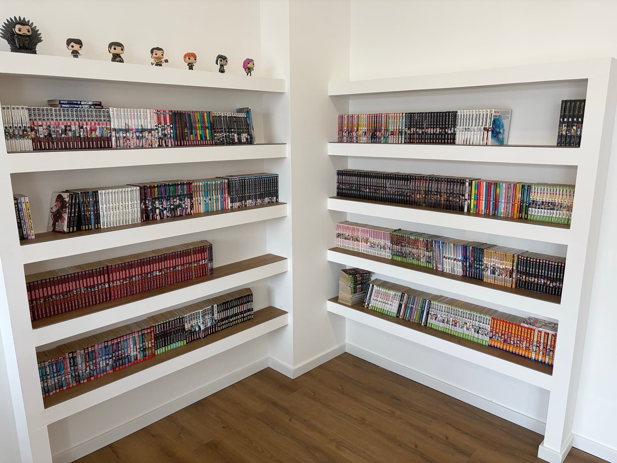 Les étagères de manga en libre lecture : des dizaines de séries complètes alignées et des figurines